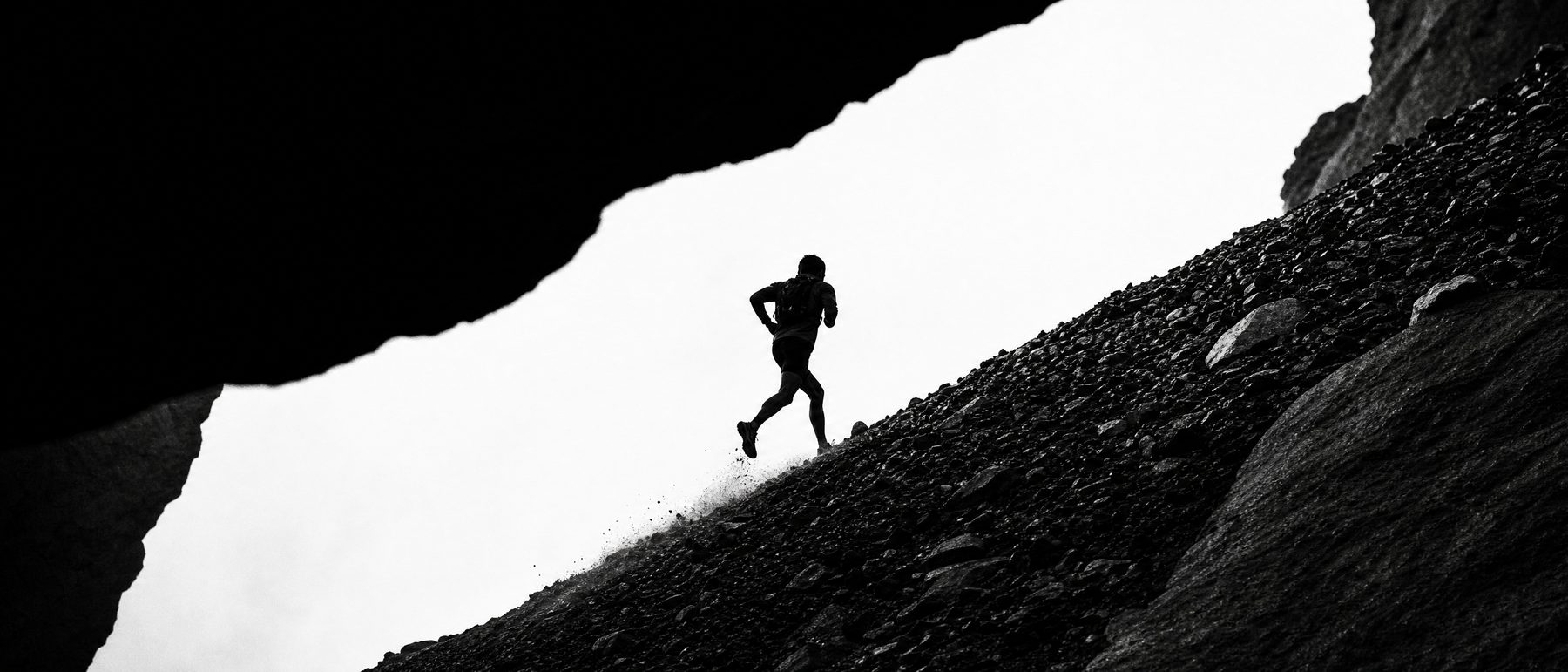 A runner on a steep scree slope, late light.